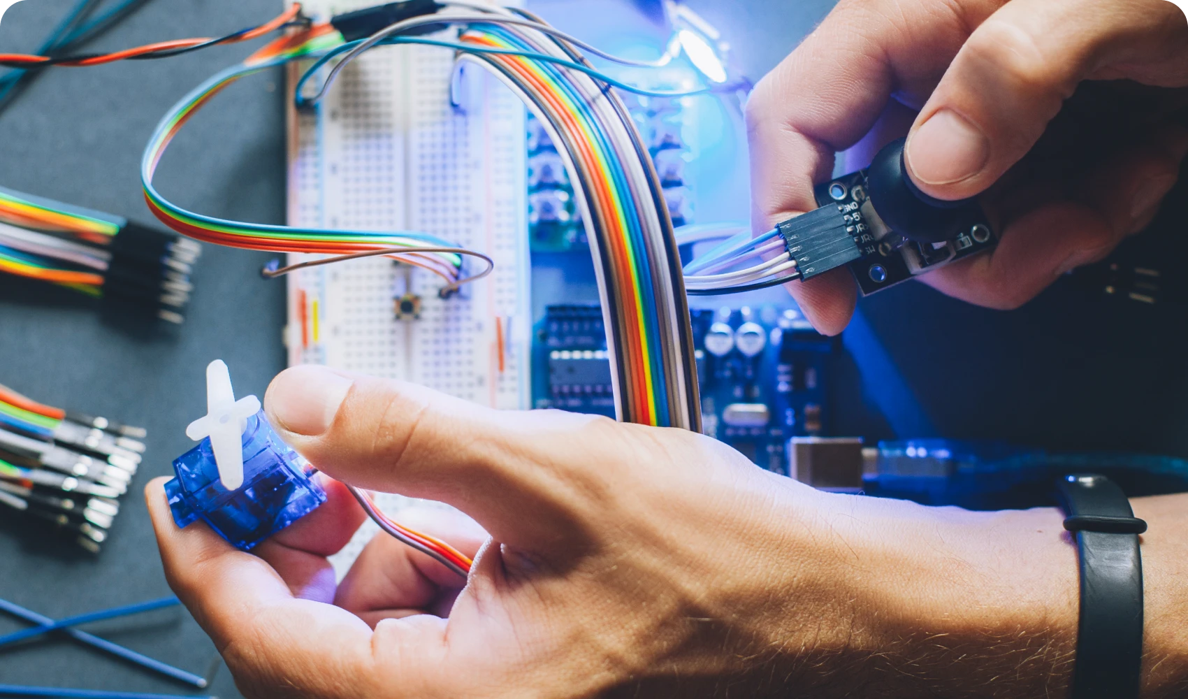 Hands working on electronics with wires